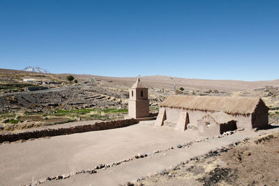 Built structure on landscape against clear blue sky