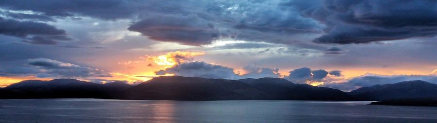 Scenic view of lake and mountains against cloudy sky