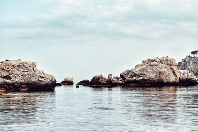 Rocks in sea against sky