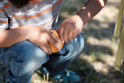 Close-up of child peeling an orange