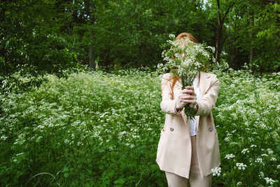 Woman standing against plants and trees