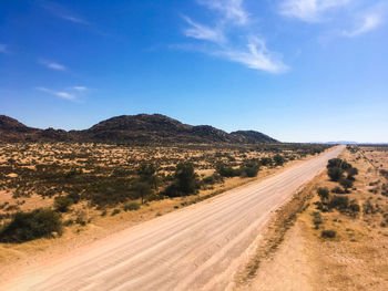 Road passing through desert against sky