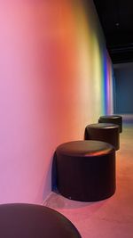 Empty chair against illuminated wall