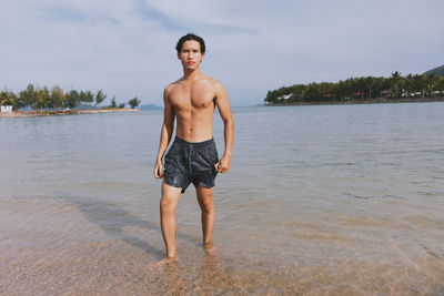 Rear view of shirtless man standing at beach