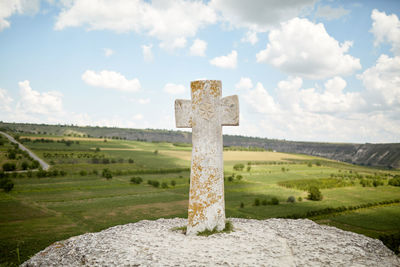 Cross stone monument on hill against a panoramic view of the canyon