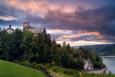 Trees and buildings against sky during sunset