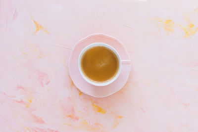 Espresso coffee in porcelain cup on pastel pink background. flat layout, top view, copy space