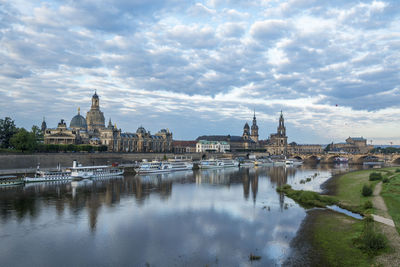 Buildings by river against sky