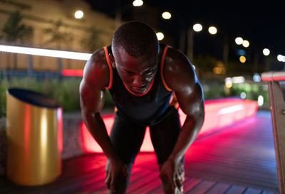 African american runner resting on night street