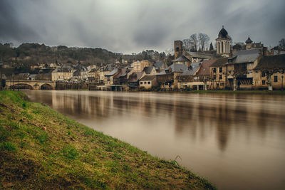 River by houses against sky in city