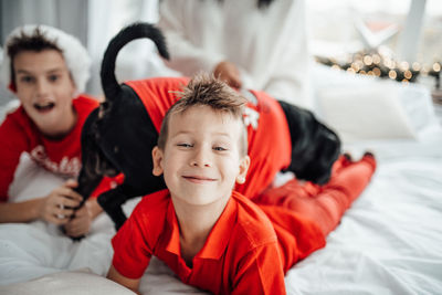 Portrait of smiling kids with dog on bed at home