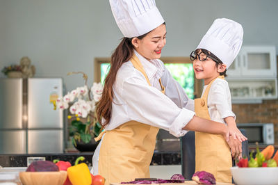 Happy friends preparing food on table at kitchen