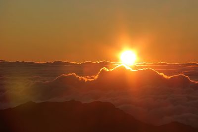 Sun shining through clouds over mountain