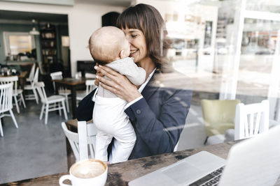 Businesswoman in cafe holding baby