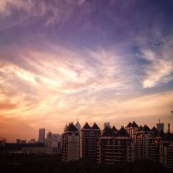 Buildings against cloudy sky at sunset