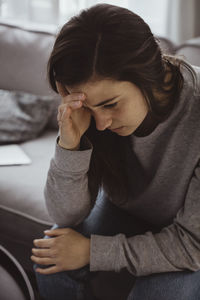 Worried woman sitting on sofa at home