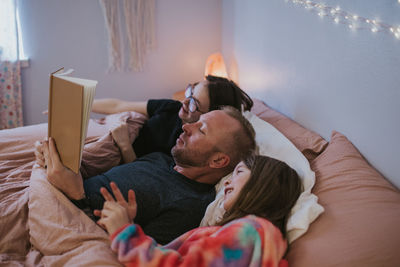 Portrait of father reading to daughters