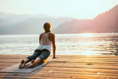 Woman exercising on pier during sunrise