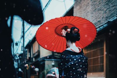 Rear view of woman with red lanterns hanging against sky