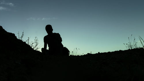 Low angle view of silhouette man on field against sky at dusk
