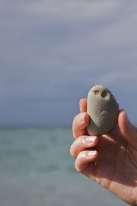 Close-up of hand holding sea against sky