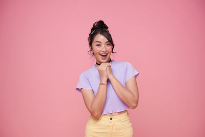 Portrait of smiling young woman against pink background