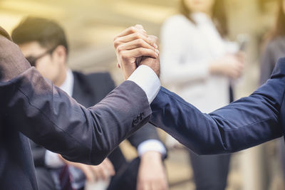 Cropped image of businessmen holding hands outdoors