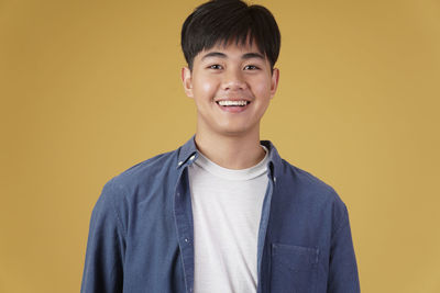 Portrait of a smiling young man against yellow background