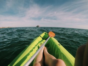 Low section of person relaxing in sea against sky