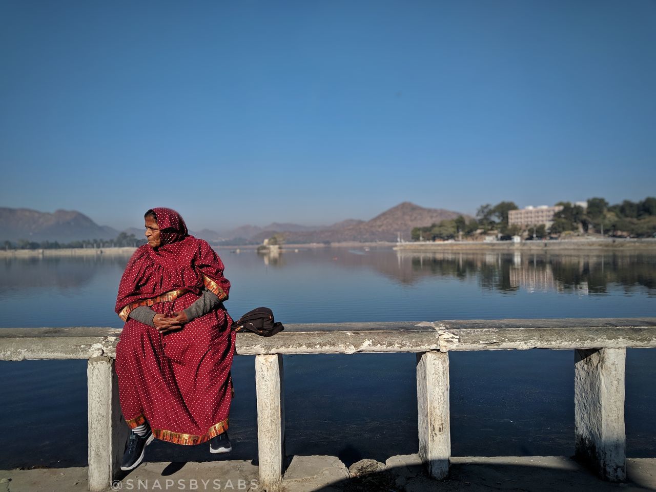 REAR VIEW OF WOMAN SITTING AGAINST BLUE SKY