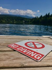 Information sign by lake against sky