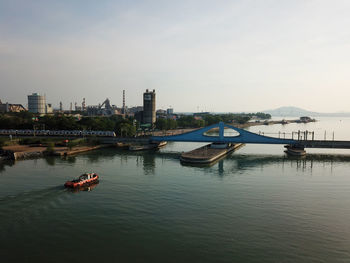Boats in river against sky in city