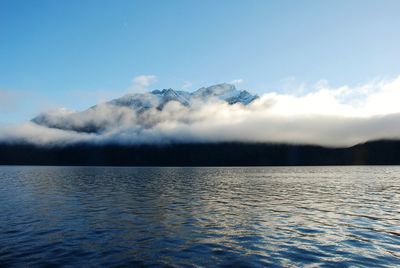 Scenic view of sea by mountain against sky