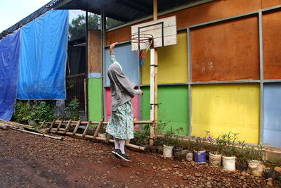 Rear view of woman standing outside house