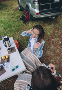 High angle view of woman photographing friend through camera in camp