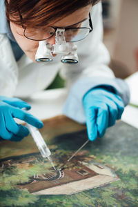 Conservator restoring an old oil painting, revitalizing canvas with syringe