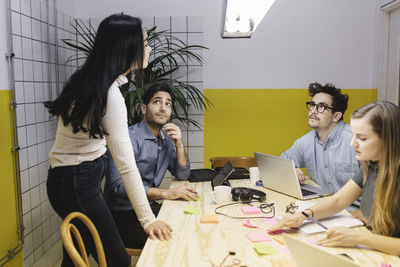 Four people discussing at desk in creative office