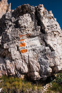 Low angle view of text on rock against sky