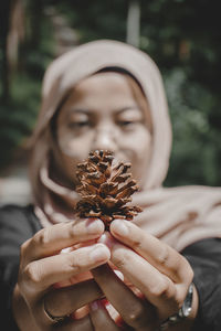 Close-up portrait of woman holding cigarette against blurred background