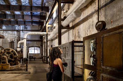 Back view of a woman exploring an old abandoned factory.