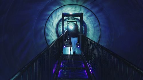 Rear view of man walking on escalator