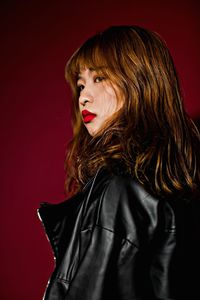 Portrait of beautiful young woman against red background