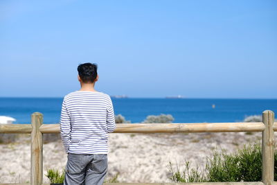 Rear view of man looking at sea against sky