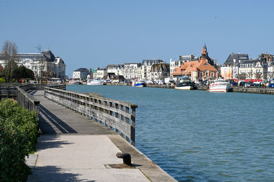 Bridge over river by buildings against clear sky