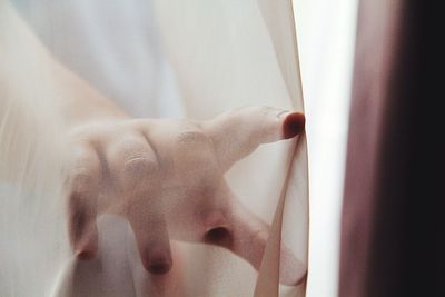 Close-up of hand touching curtain