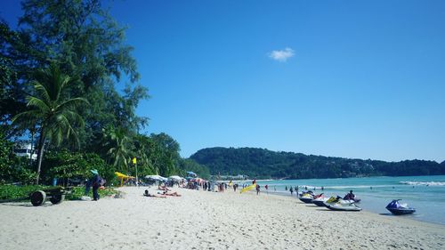 People on beach against blue sky