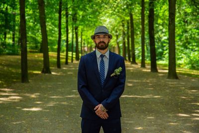 Portrait of bridegroom wearing suit standing in forest