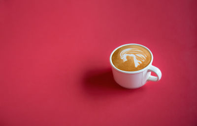 Close-up of coffee cup against red background