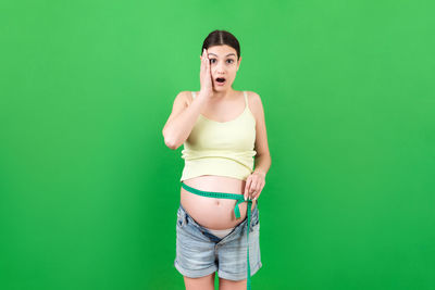 Portrait of woman standing against green background