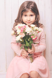 Smiling girl holding bouquet while sitting at home